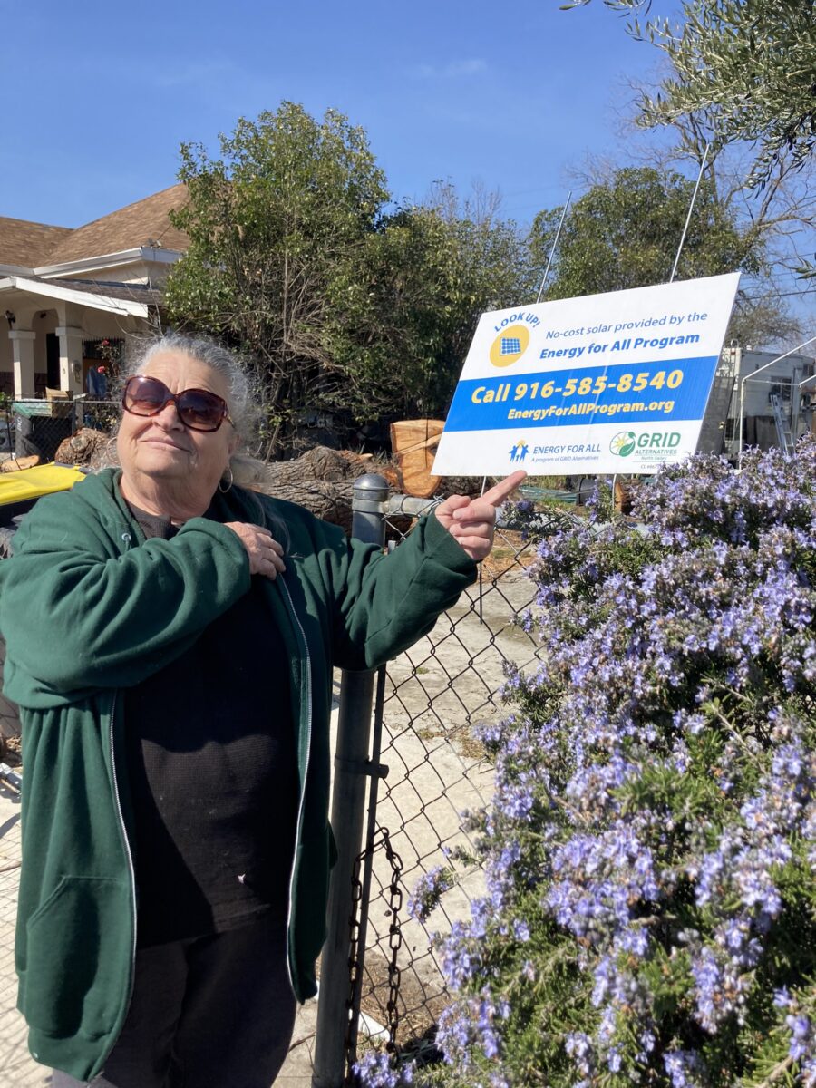 Stockton resident and GRID client Patricia Barret in front of Energy for All lawn sign