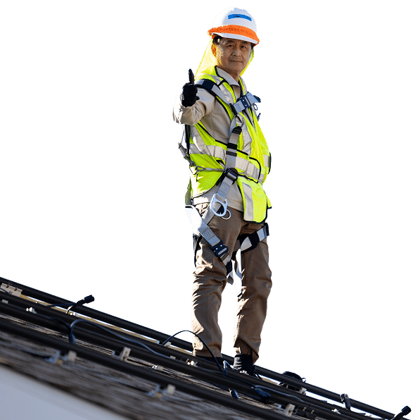 Construction worker on roof wearing safety gear gives thumbs up