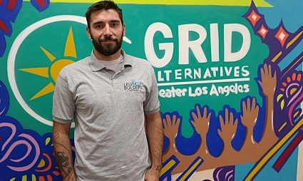 Man standing in front of GRID Alternatives Greater Los Angeles colorful mural with hands design