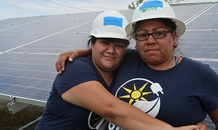 Marisa and Arissa embrace in front of the solar PV system.