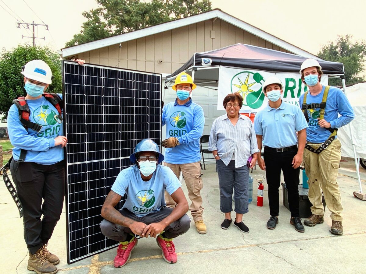 GRID team members and homeowner pose with large solar panel installation at residential home