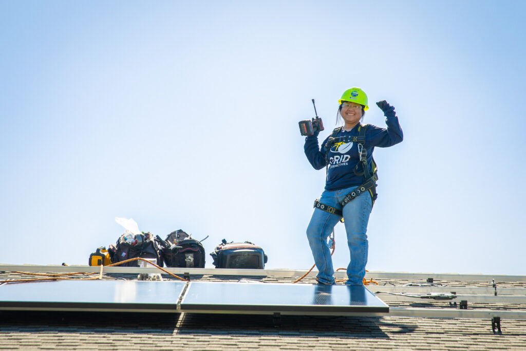 Worker in safety gear standing on rooftop with solar panels and equipment