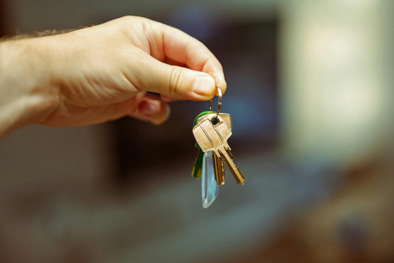 Hand holding a bundle of brass keys on a keyring with green accent