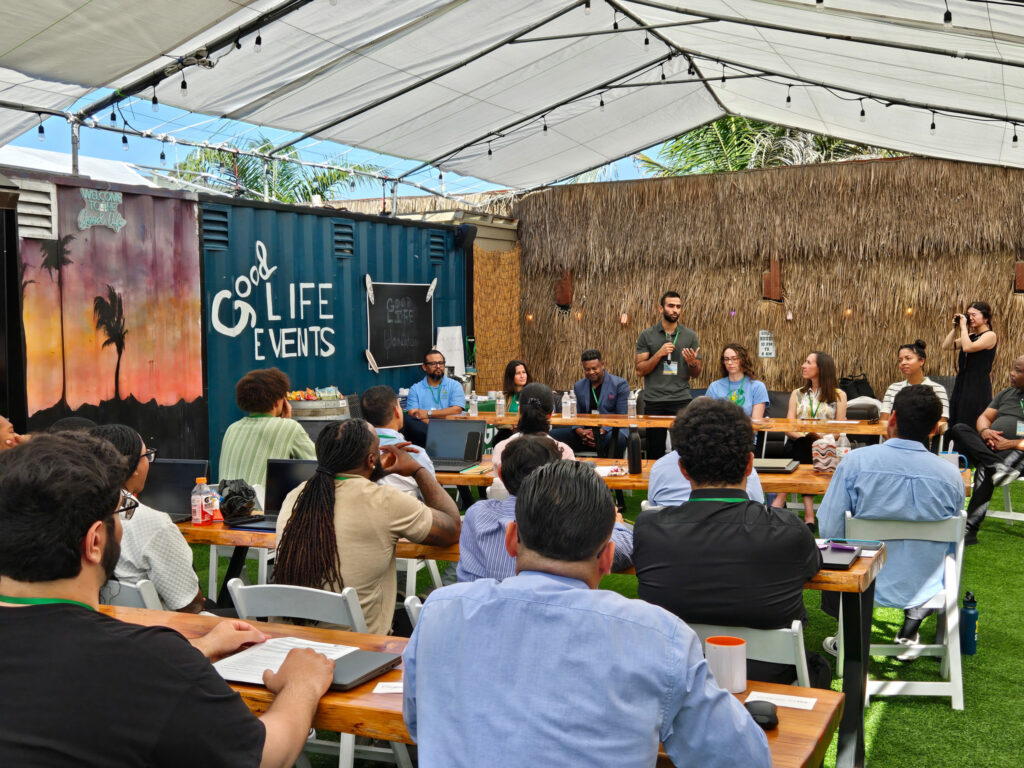 Good Life Events panel discussion with seated audience members at wooden tables under shade structures