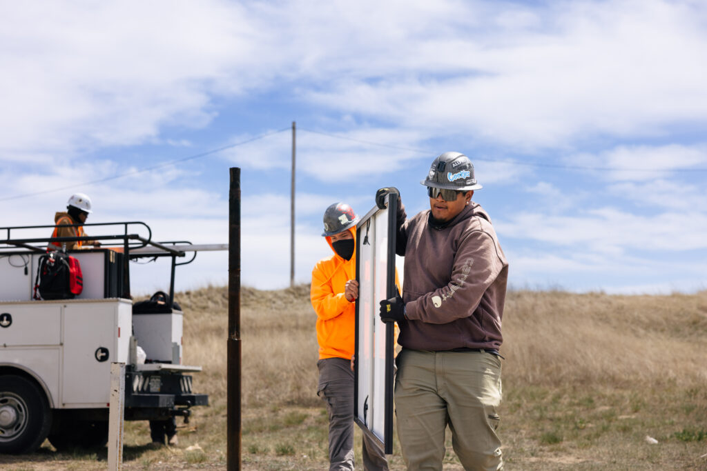 Two native installers carrying solar panel