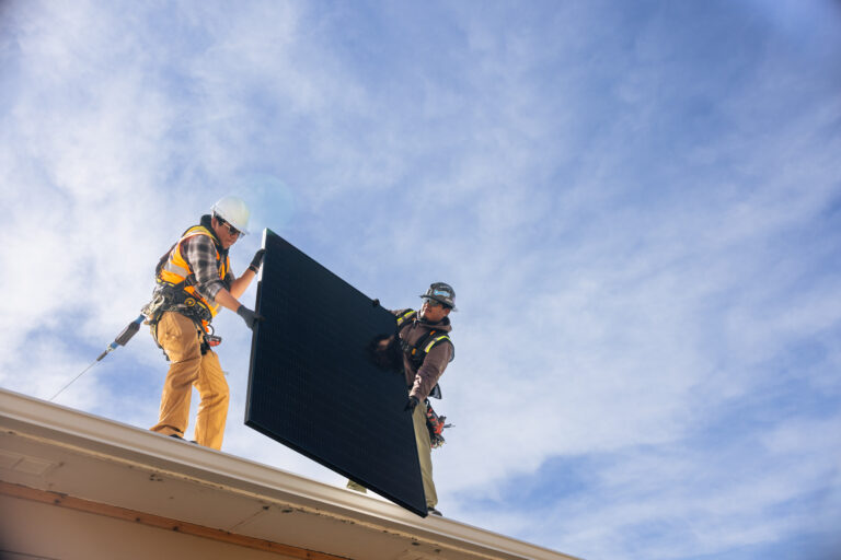 2 installer on roof holding solar panel