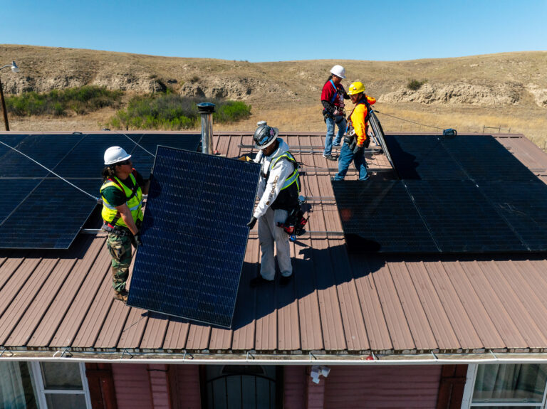 tribal solar installation, panels on roof with 4 installers