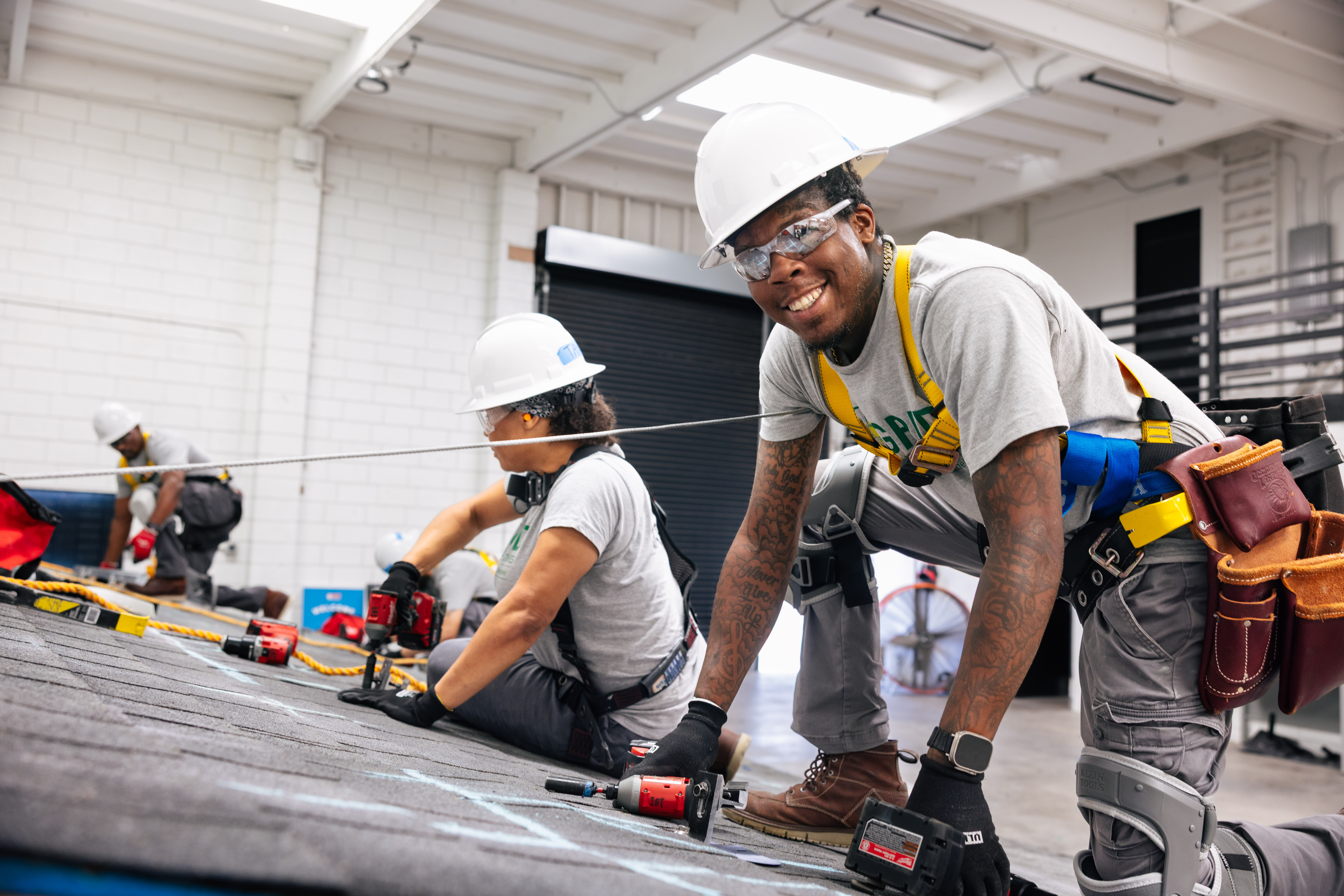 Two construction workers installing roofing material on an industrial building during a training program