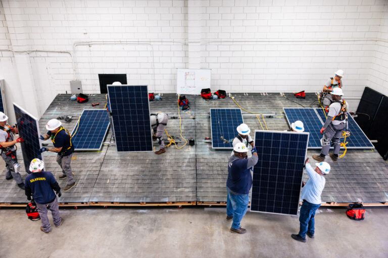 Solar panels on training roof, with installers and safety equipment