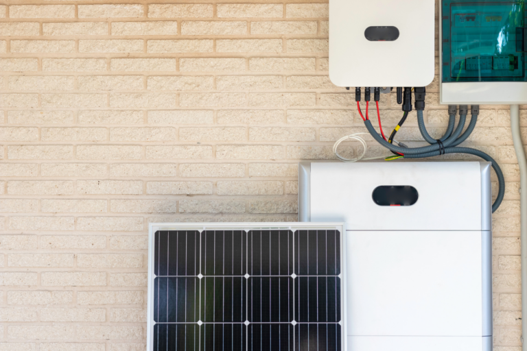 Solar panel and white battery storage system mounted on brick wall with electrical wiring