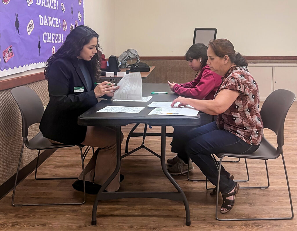 Outreach Manager, Yoselyn S., verifying program application documents with a workshop attendee.