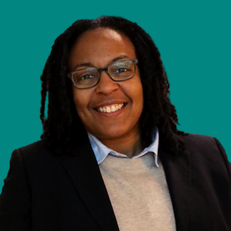 Erika Symmonds, professional headshot of a woman wearing glasses and blazer against teal background