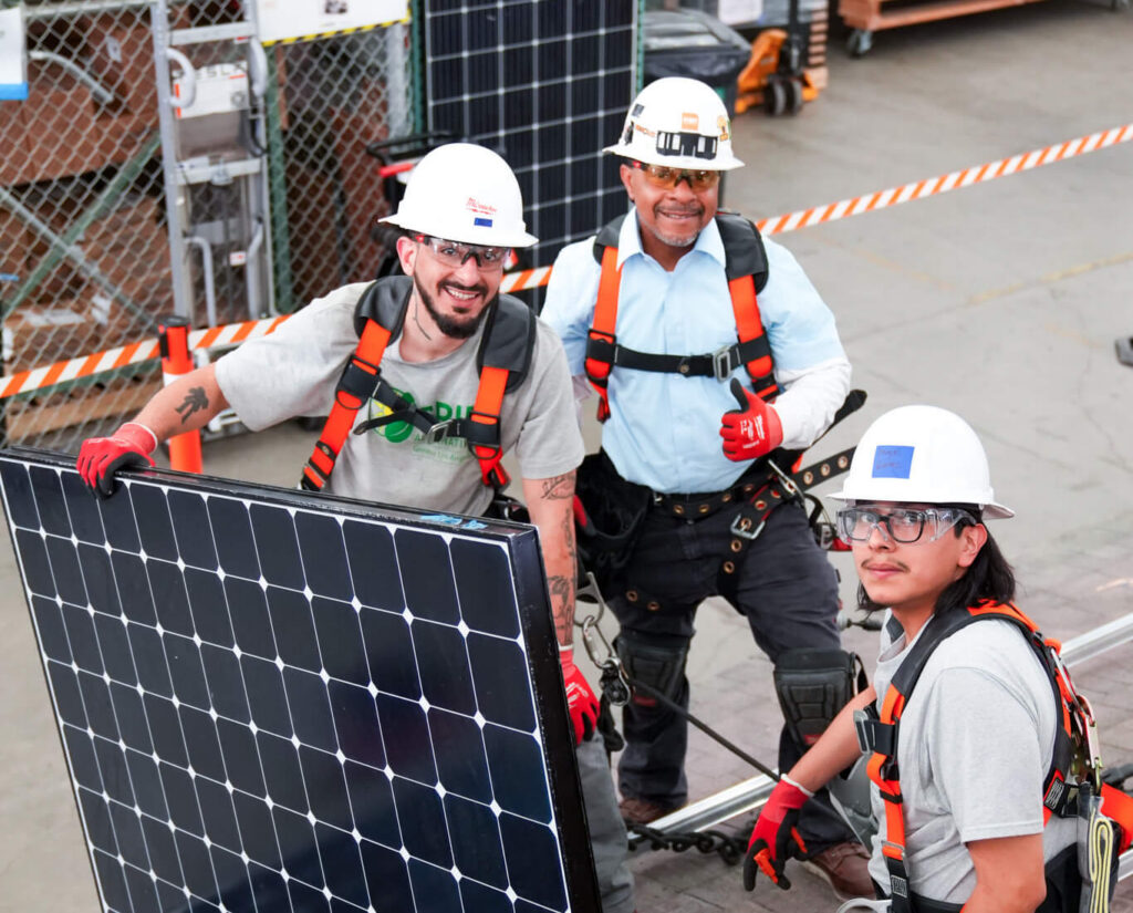 People on a roof holding a solar panel