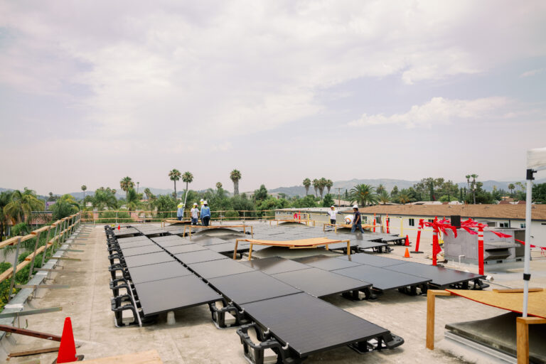 Solar panels installed on industrial rooftop with mountains visible in background