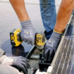 Workers installing solar panels on a roof with power tools and protective gloves