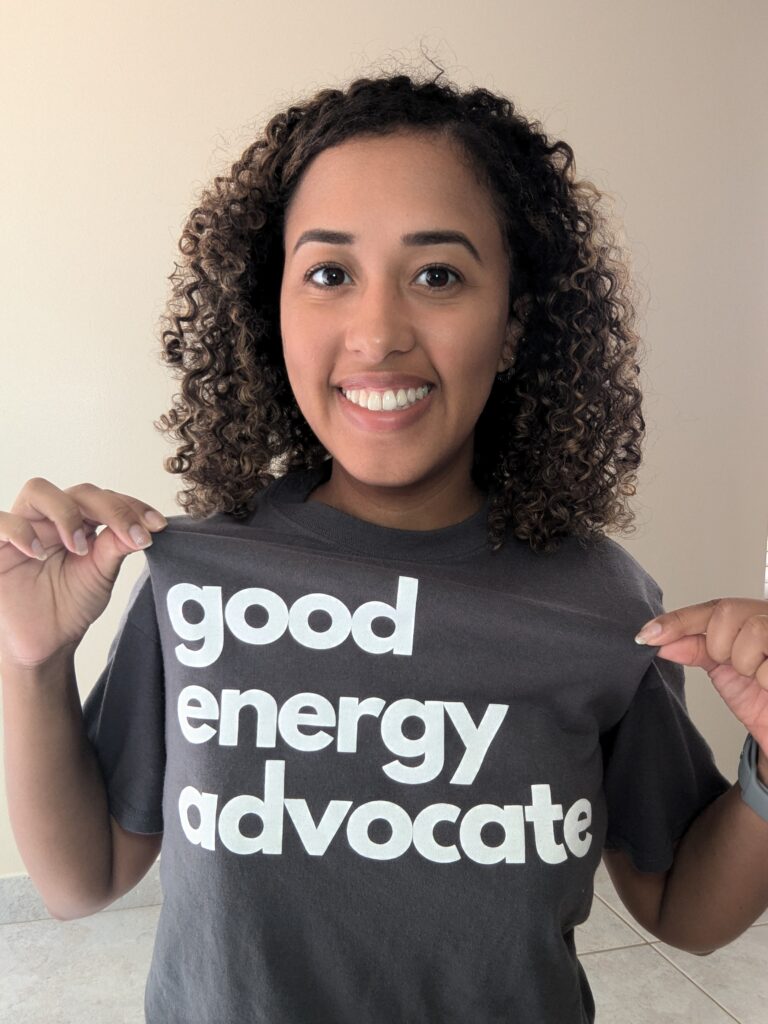 Smiling woman wearing a dark gray t-shirt that reads "good energy advocate