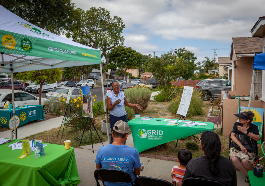 GRID Alternatives outdoor community event with green branded tents and tables in residential neighborhood