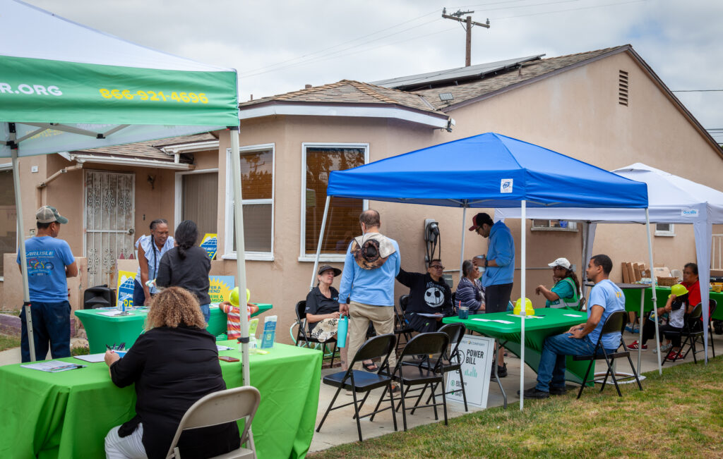 GRID Alternatives outdoor community event with green branded tents and tables in residential neighborhood